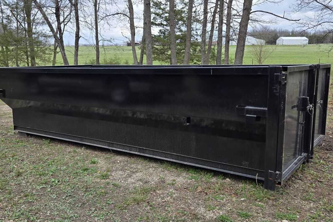 Empty black roll-off dumpster set in a yard